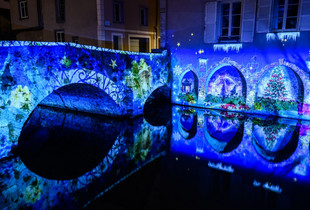 Vue sur une scénographie de Chartres en lumières de Noël sur le pont et se reflétant sur l'Eure