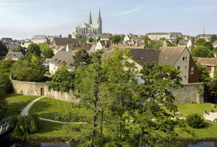 Vue sur la cathédrale depuis la rivière, avec un square arboré et l'ancien rempart de la ville