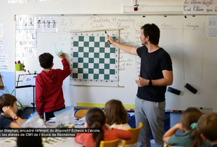 Un professeur devant un tableau enseignant les Échecs à une classe de CM1