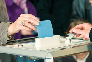 women 's hand vote La main d'une personne déposant un bulletin de vote dans une urne.