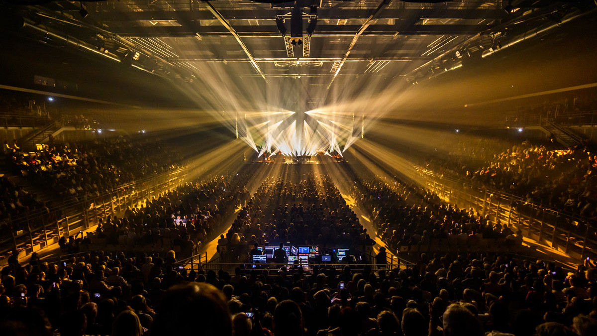 Un concert au Colisée avec une salle comble et des projecteurs illuminant la scène