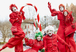 Personnages et échassiers rouges et blancs en parade de Noël