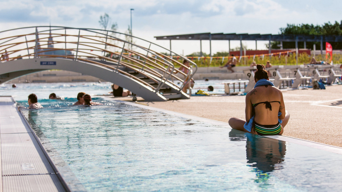 Le piscine extérieure de l'Odyssée avec des nageurs en train de nager ou de se reposer sur le bord du bassin