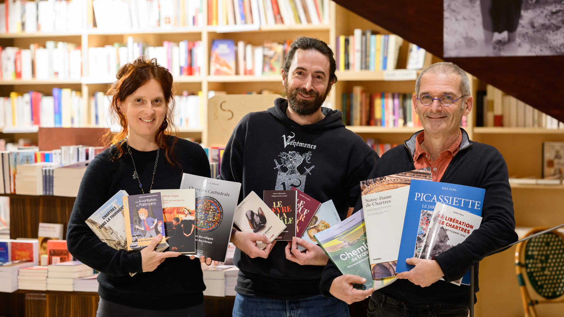 Trois libraires tenant des livres dans leurs bras