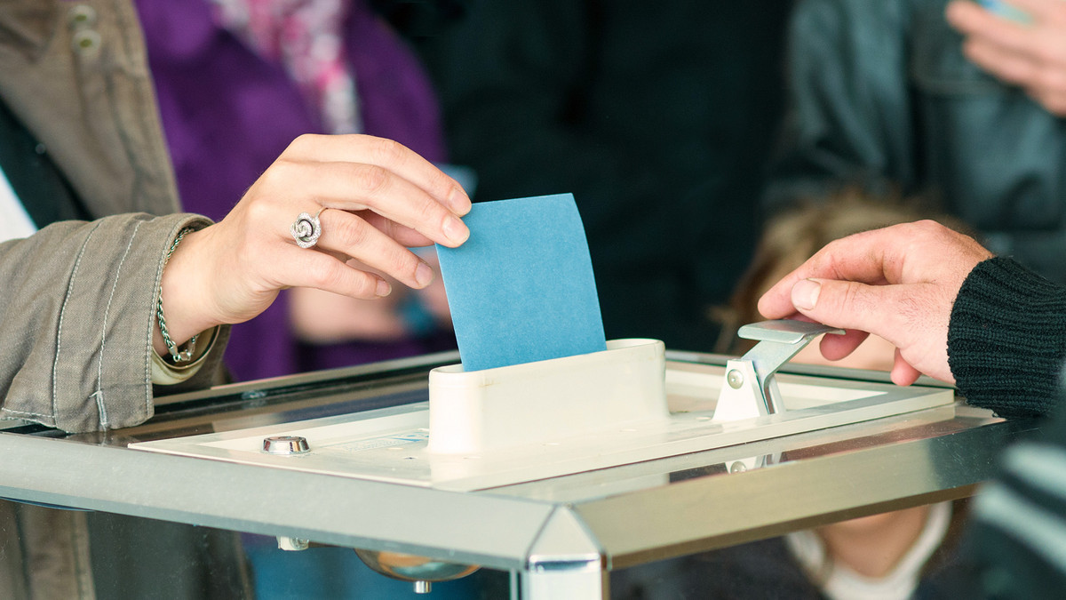 women 's hand vote La main d'une personne déposant un bulletin de vote dans une urne.