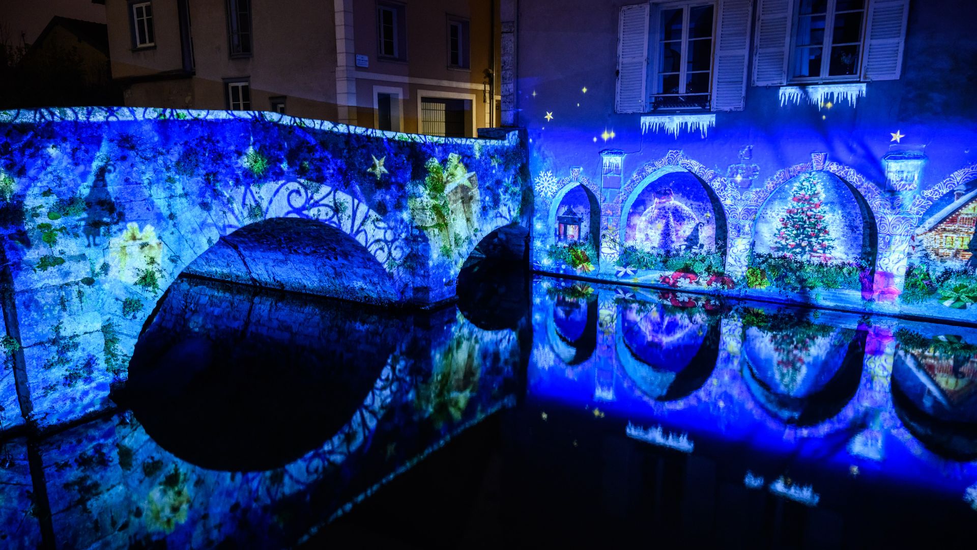 Vue sur une scénographie de Chartres en lumières de Noël sur le pont et se reflétant sur l'Eure